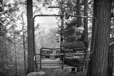 Natalie riding a chairlift through the woods.